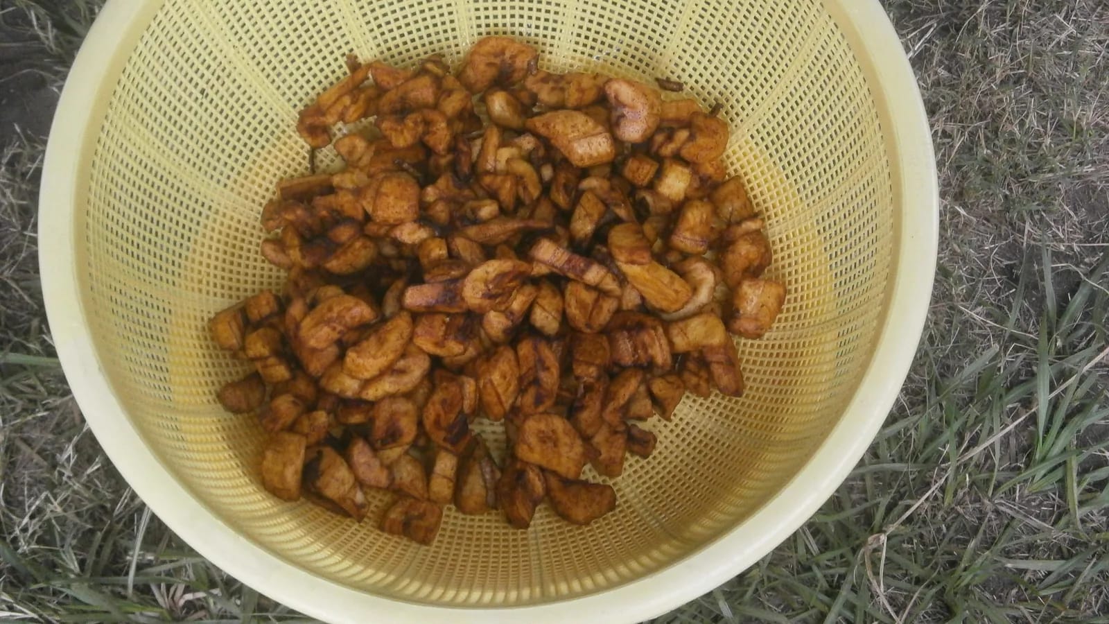 Alloco doré sorti de la friture, égoutté dans une passoire