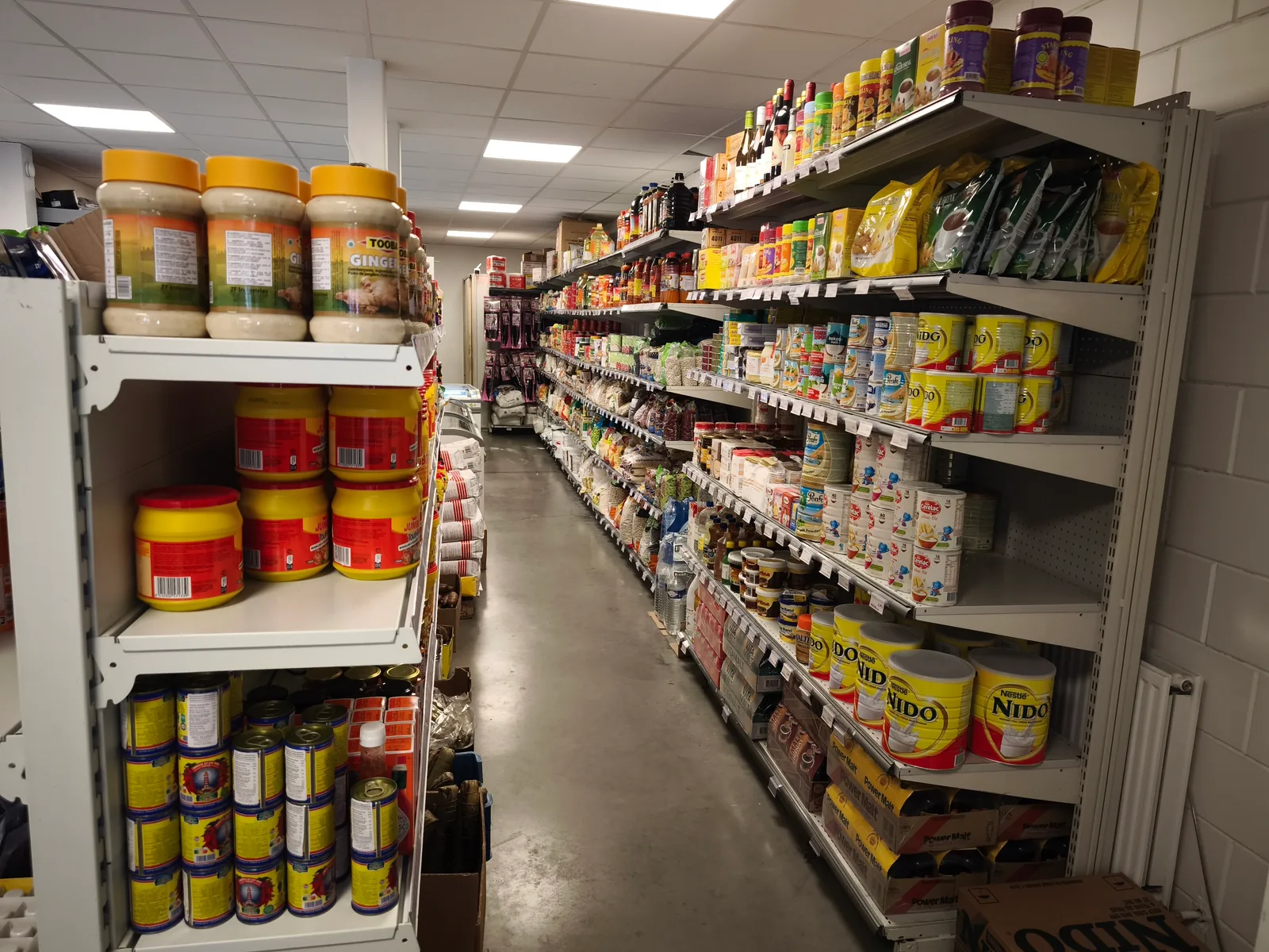 Rayons remplis du magasin Nkoh Shop : pâte d'arachide, lait Nido, conserves, riz
